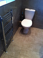 Ensuite shower room after renovation. New grey 450x450mm ceramic tiles floor and wall, new slim line w/c, and chrome towel radiator. (Guildford)